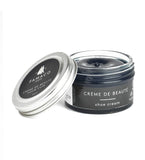 Open Famaco navy shoe cream jar, angled close-up showing glossy wax surface with lid resting beside it